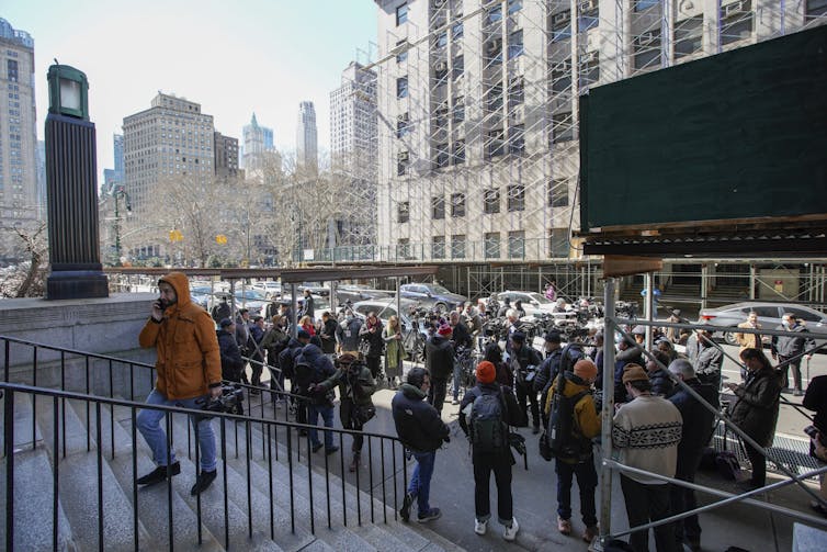 People with cameras standing in front of the stairs to a building.