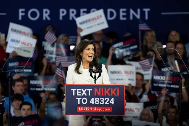 With dozens of her supporters behind her, Nikki Haley stands before a lectern at a campaign rally.