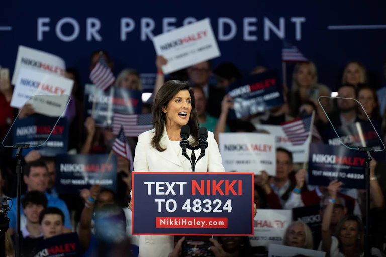 With dozens of her supporters behind her, Nikki Haley stands before a lectern at a campaign rally.