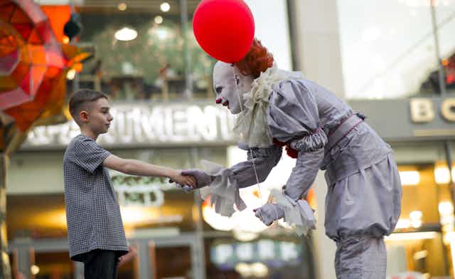 clown sert la main d'un enfant