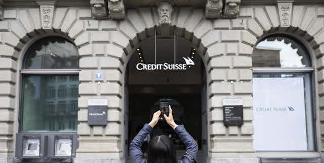 A woman takes photo of Credit Suisse bank branch in Zurich, Switzerland, March 20 2023. 