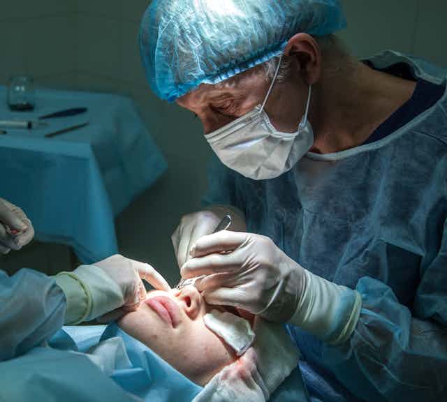 Surgeon working on woman's face
