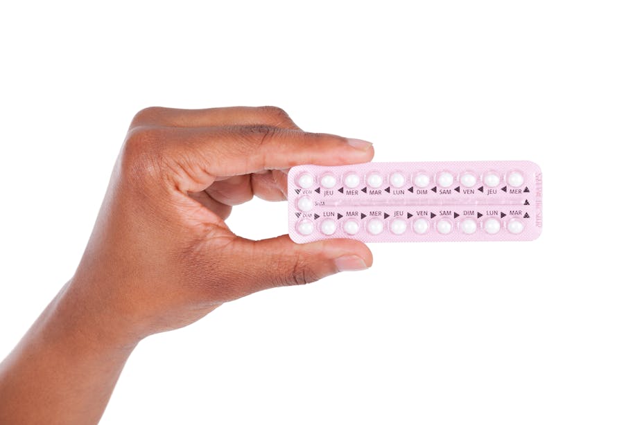 A woman holds a blister pack of birth control pills in her hand.