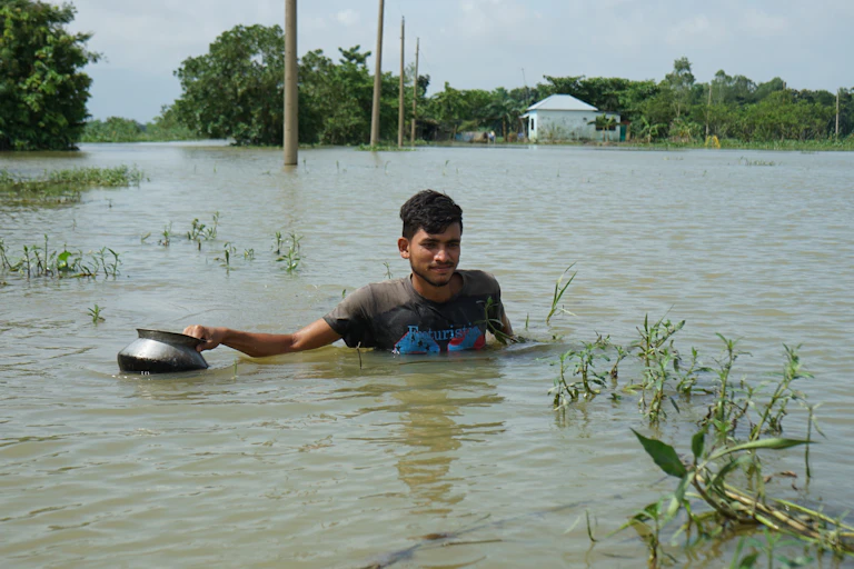 Joven avanza sumergido en el agua por la inundación.