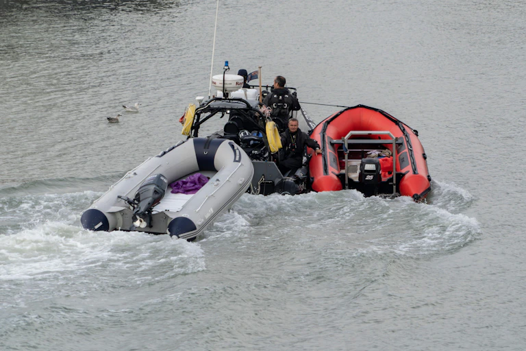 A Border Force boat pulling two empty dinghies into port