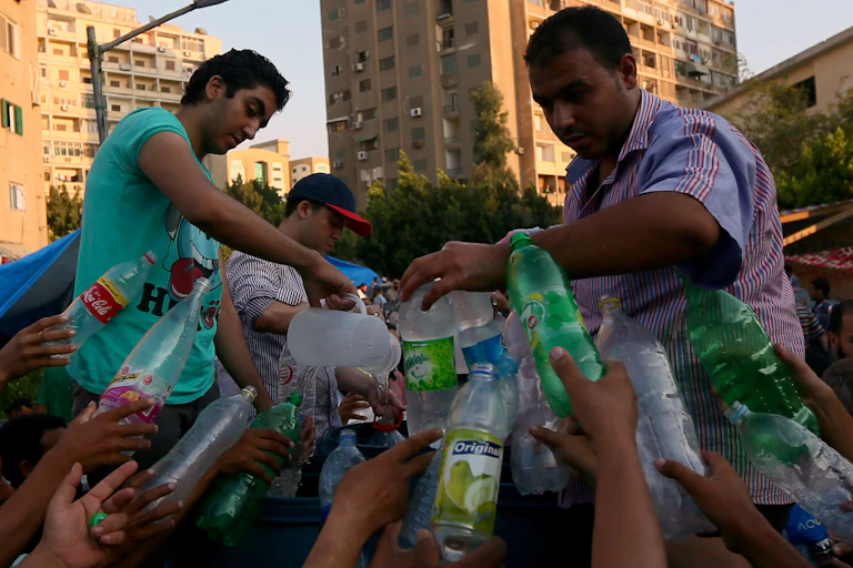 Men fill up water bottles from a jug.