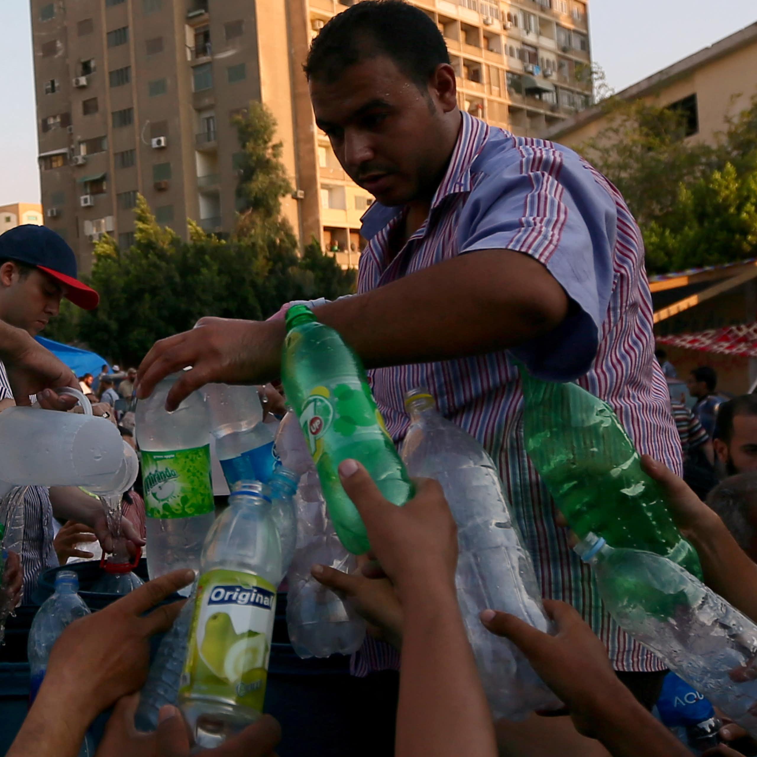 Men fill up water bottles from a jug.