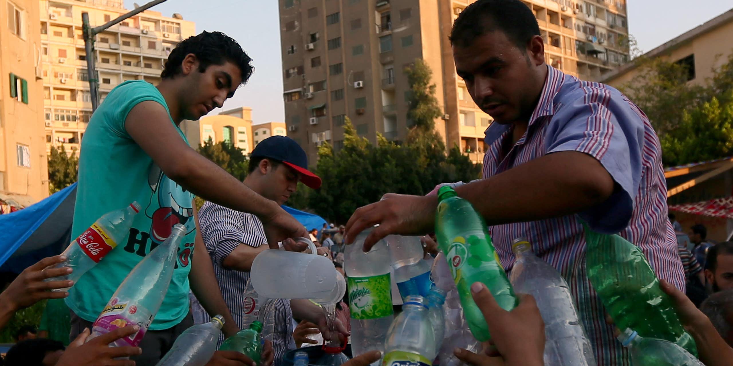 Men fill up water bottles from a jug.