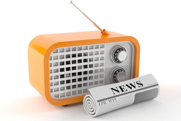 An orange radio with a rolled up newspaper in front of it.