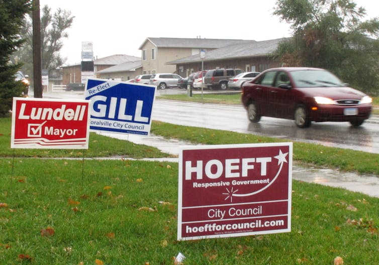 Letreros en el césped en diferentes colores anunciando candidatos locales.