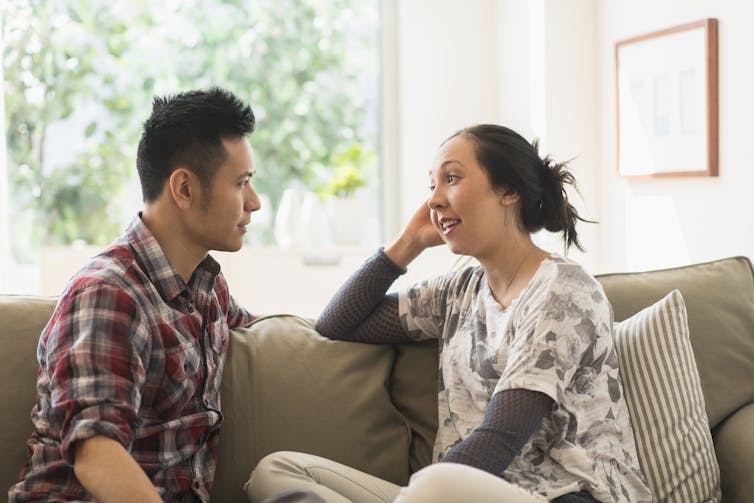 Couple talking on sofa in living room.