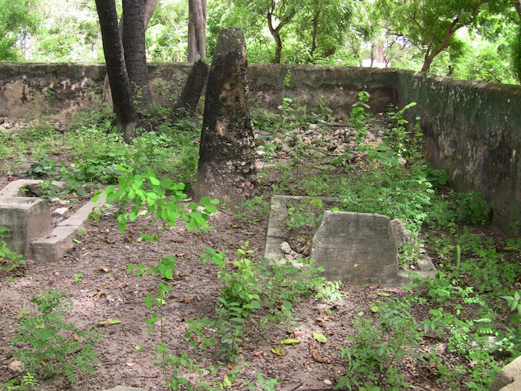 woodsy setting with a stone wall enclosing an area with grave stones
