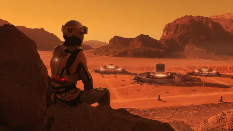 An artist's concept of an astronaut on Mars, sitting against a rock and gazing at the space colony sitting in the distance on dusty orange flatland.