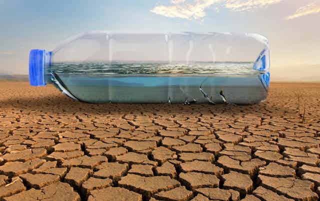 A bottle of water on cracked dry land.