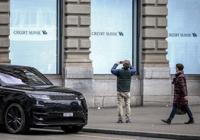 Un homme prend une photo d'un panneau de la banque Credit Suisse à son siège à Zurich le 20 mars 2023
