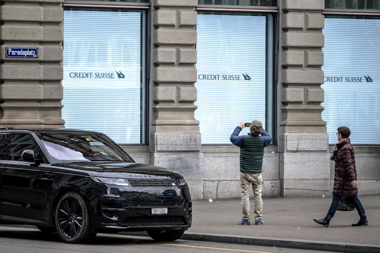 Un homme prend une photo d'un panneau de la banque Credit Suisse à son siège à Zurich le 20 mars 2023