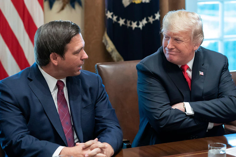 Two men wearing blue jackets and red ties.