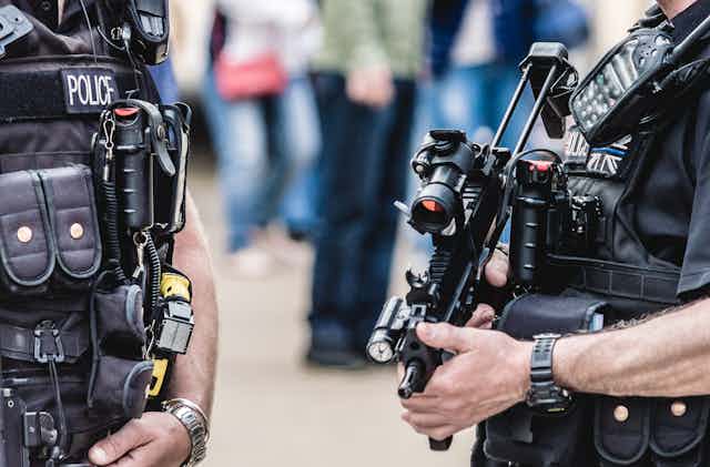 Close up of chests of two UK police officers with firearms and bulletproof gear
