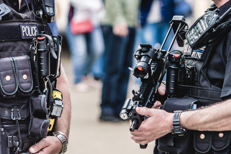 Close up of chests of two UK police officers with firearms and bulletproof gear