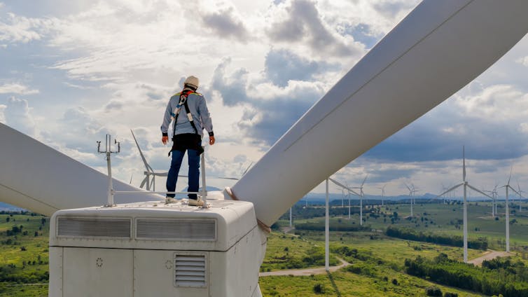 Man stands on large wind turbine