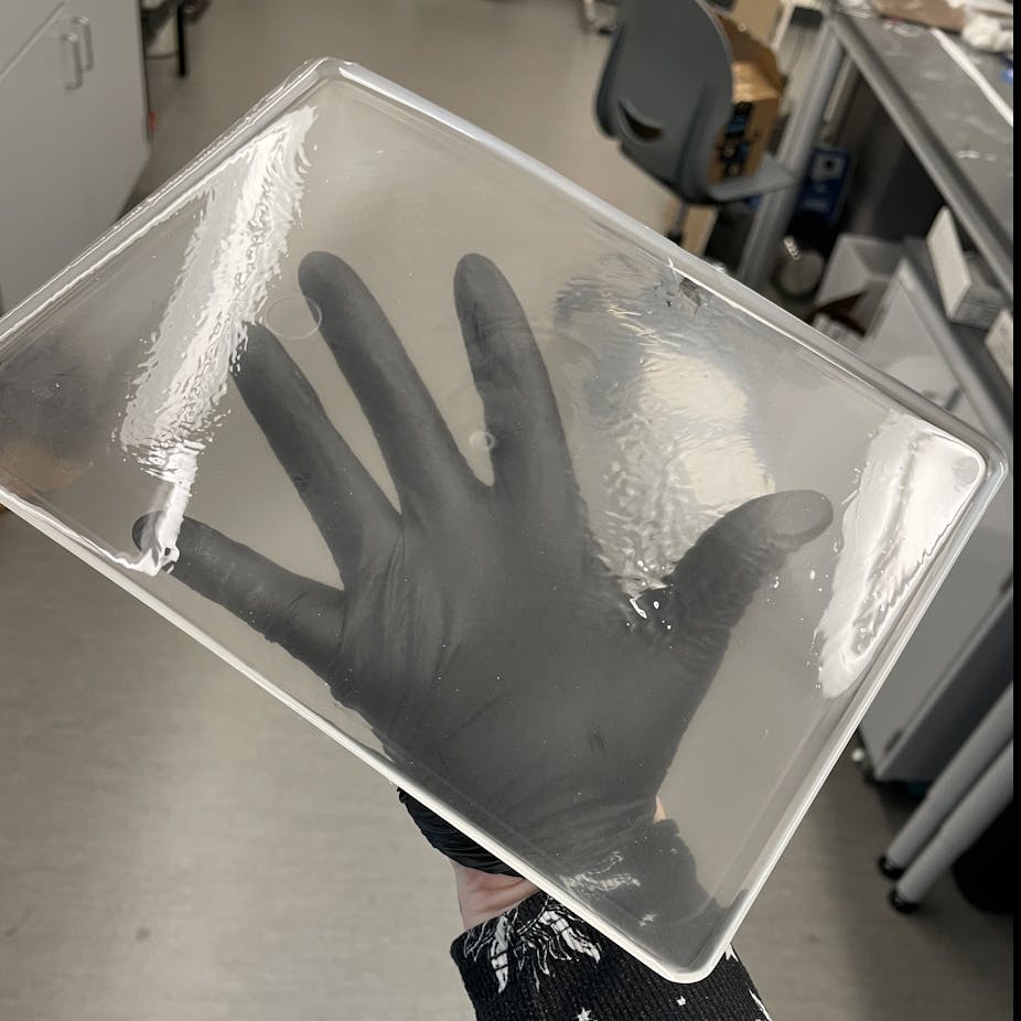 A hand holding a large, clear rectangle of plastic.