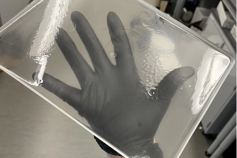 A hand holding a large, clear rectangle of plastic.