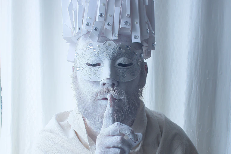 un homme costumé et masqué avec un doigt sur la bouche