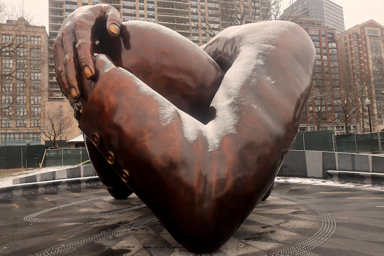 A bronze sculpture of arms embracing was built in a park.