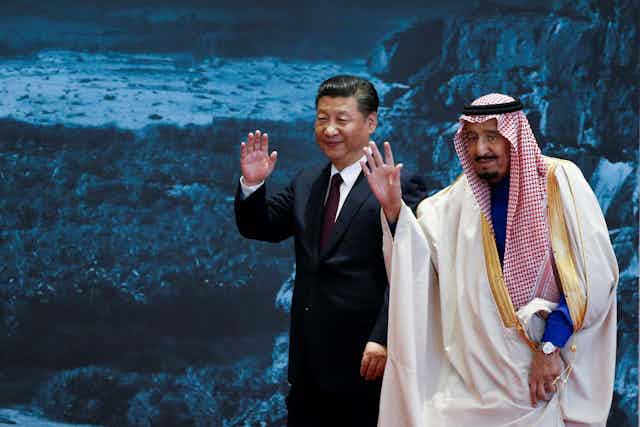 Two men, president Xi and Saudi King Salman of Saudi Arabia,  wave towards the camera.