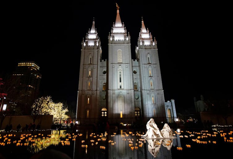 A grand-looking church building with tall spires lit up at night.