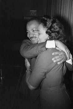 A Black man is embracing a Black woman as both of them are smiling.