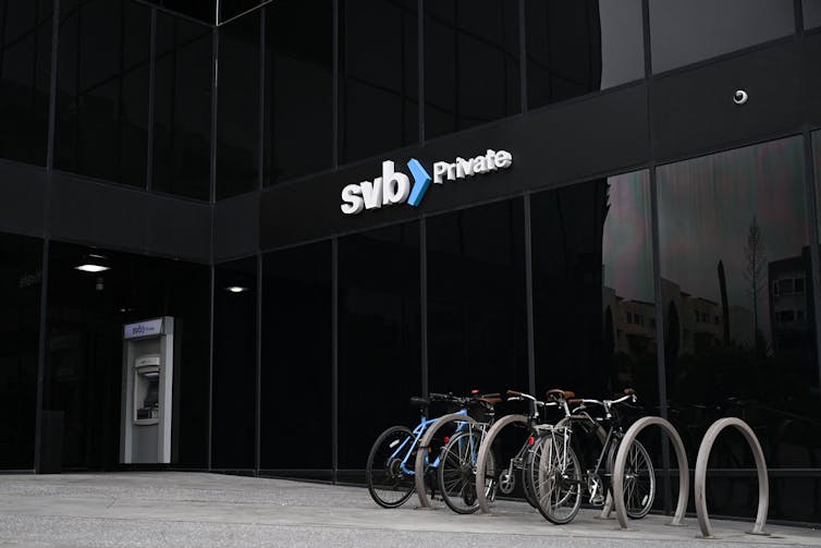 Bikes locked to a bike rack in front of a building with SVB on the front