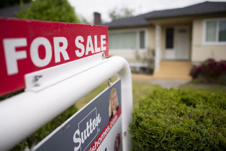 A for sale sign on the lawn of a detached house