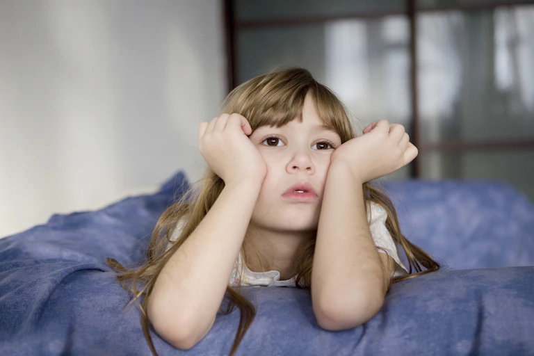 Girl in bed awake with arms up to face