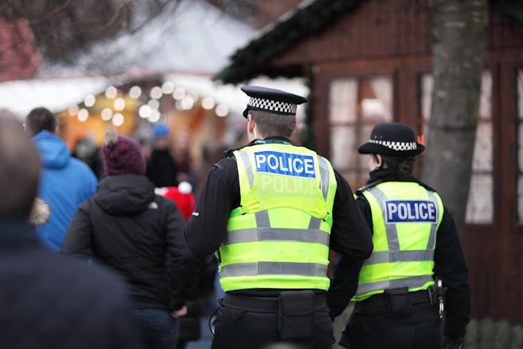 Two police officers viewed from behind, patrolling at a Christmas market.