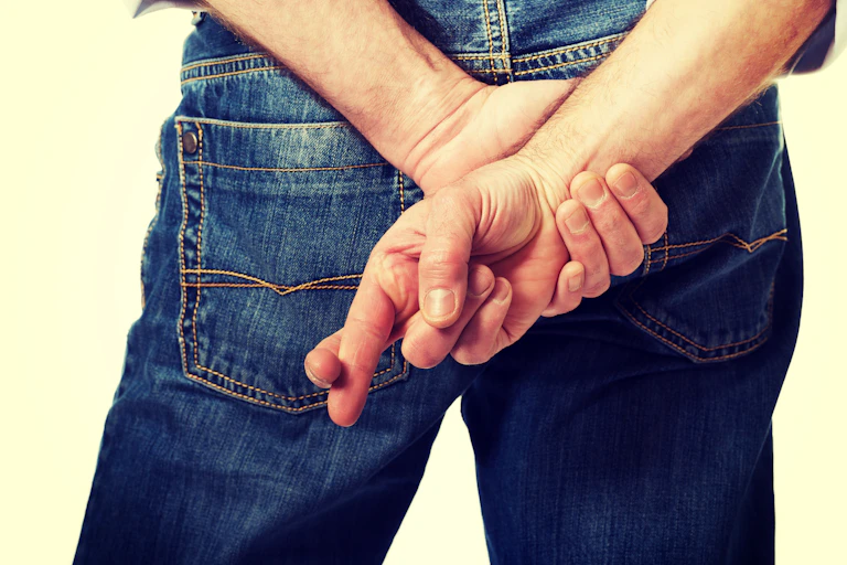 Male hands with crossed fingers.