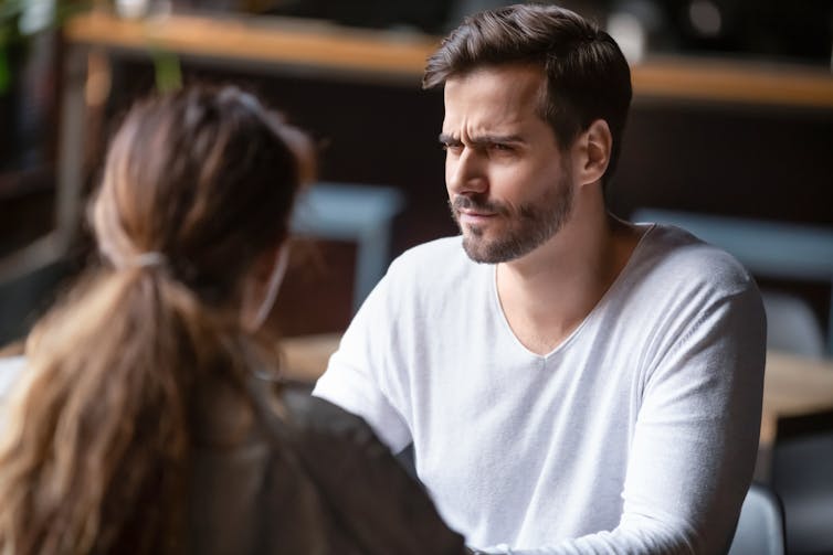 Man with doubtful expression facing woman