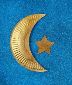 Paper cutout of a crescent moon and star are painted gold.