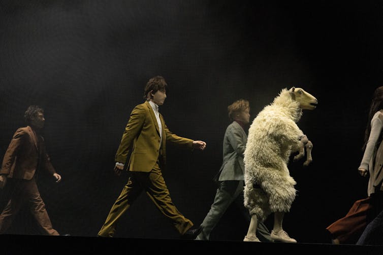 Four humans and a sheep on its hind-legs.