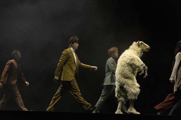Four humans and a sheep on its hind-legs.