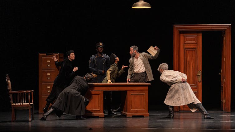Dancers around a desk.