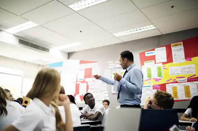 A teacher talks to students in the middle of a classroom.