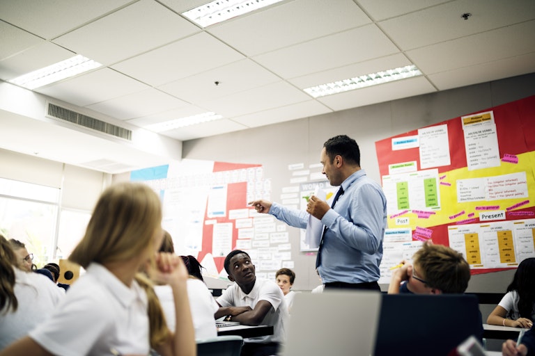 A teacher talks to students in the middle of a classroom.