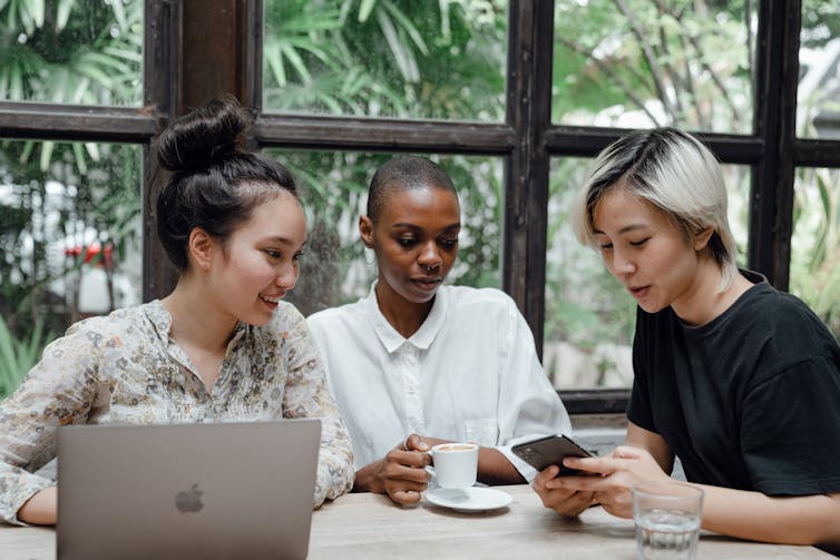 Three people look at their screens.
