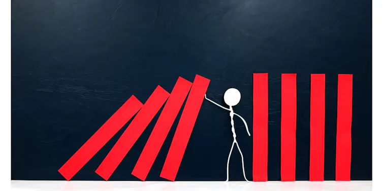 Illustration of a stick figure preventing a line of dominoes from falling over
