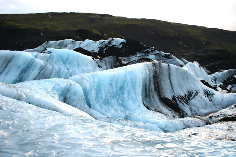 Glacial peaks beneath green rolling hills, located in Southern Iceland.