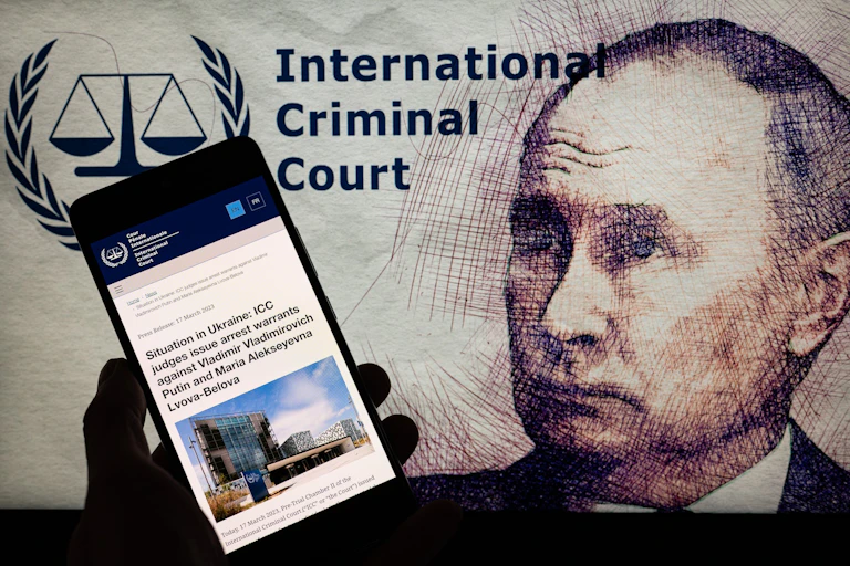Montage représentant Vladimir Poutine, le logo de la CPI et un smartphone affichant l'information de l'émission du mandat d'arrêt à son encontre