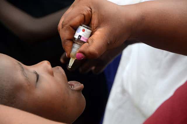 A health worker gives a dose of polio vaccine to a child 