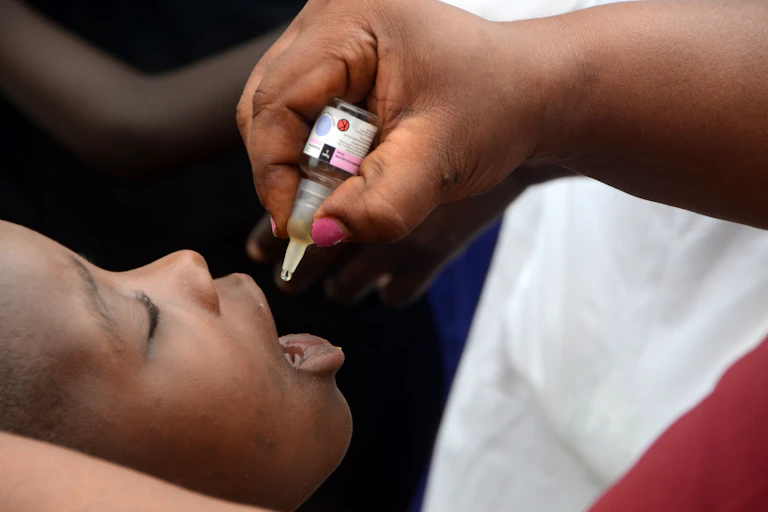 A health worker gives a dose of polio vaccine to a child