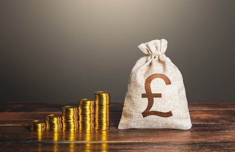 Piles of coins next to a bag of cash.